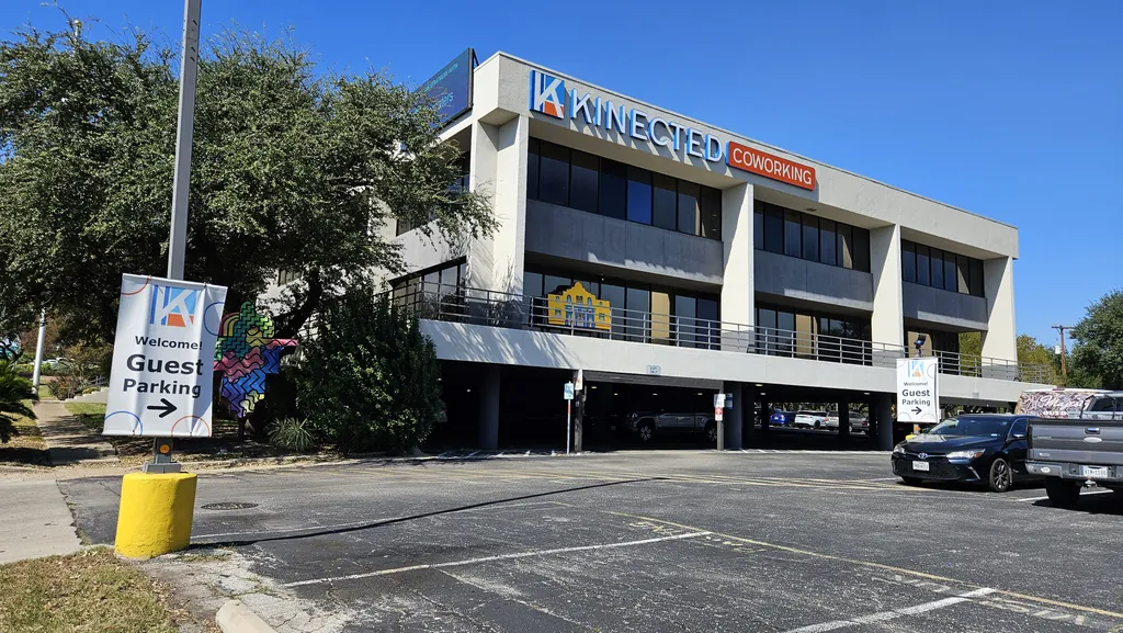 Kinected Coworking building at 10401 I-10 in San Antonio with Welcome Guest Parking signs in the lot