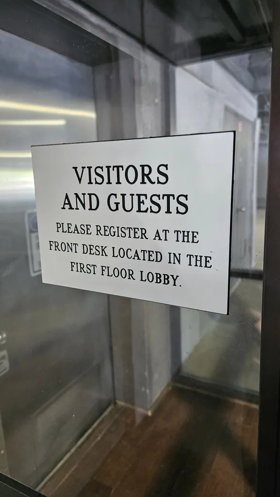 Sign asking visitors and guests to register at the front desk in the first-floor lobby