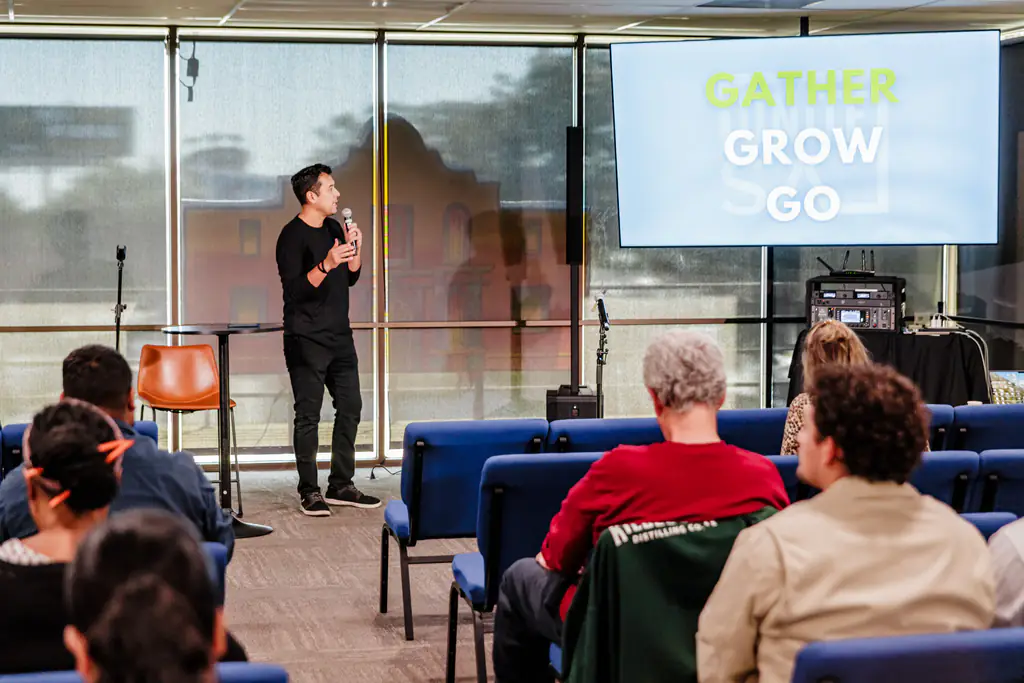 Speaker presenting to an engaged audience at a community event in the Elephant Room at Kinected Coworking in San Antonio