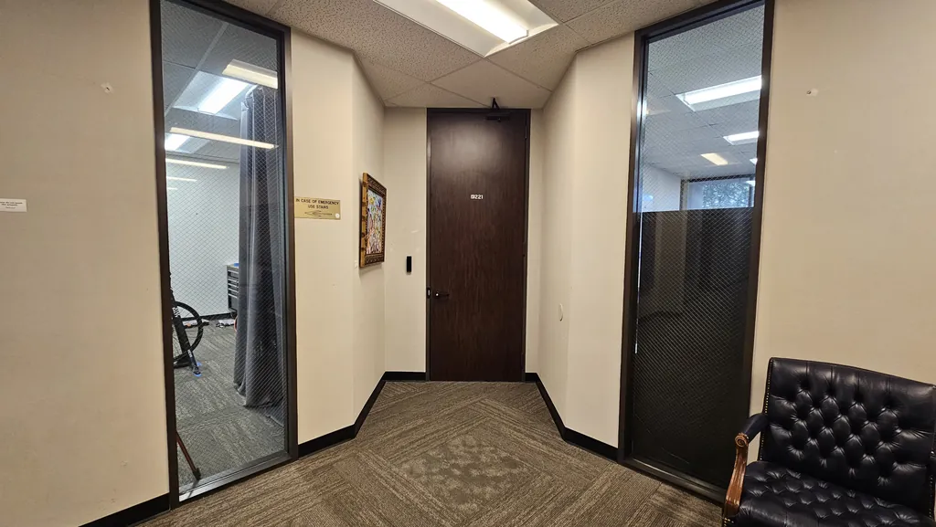 Second-floor hallway leading to Suite 221 with posted emergency stairs directions