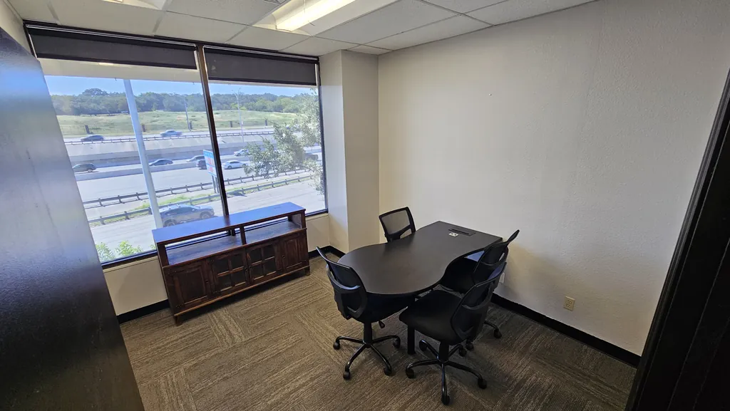 Meeting room in Suite 211 with a table for four and floor-to-ceiling windows over Interstate 10