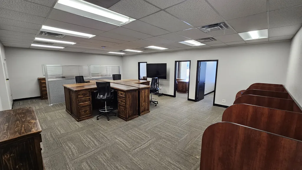 Open team area inside Suite 211 with wood executive desks, study carrels, and doors to the private offices