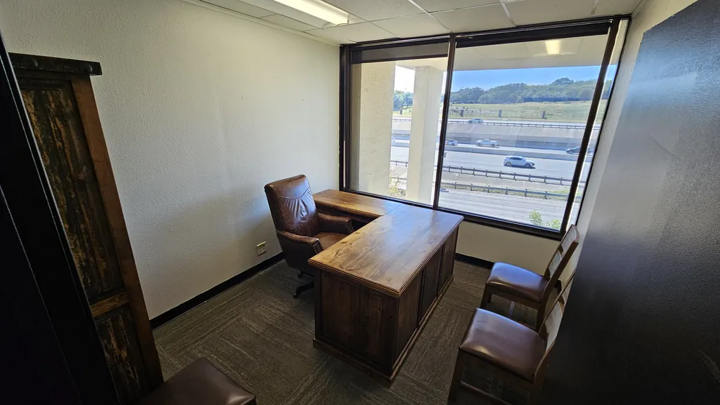 Private office in Suite 211 with a wood executive desk, leather chair, and guest chairs