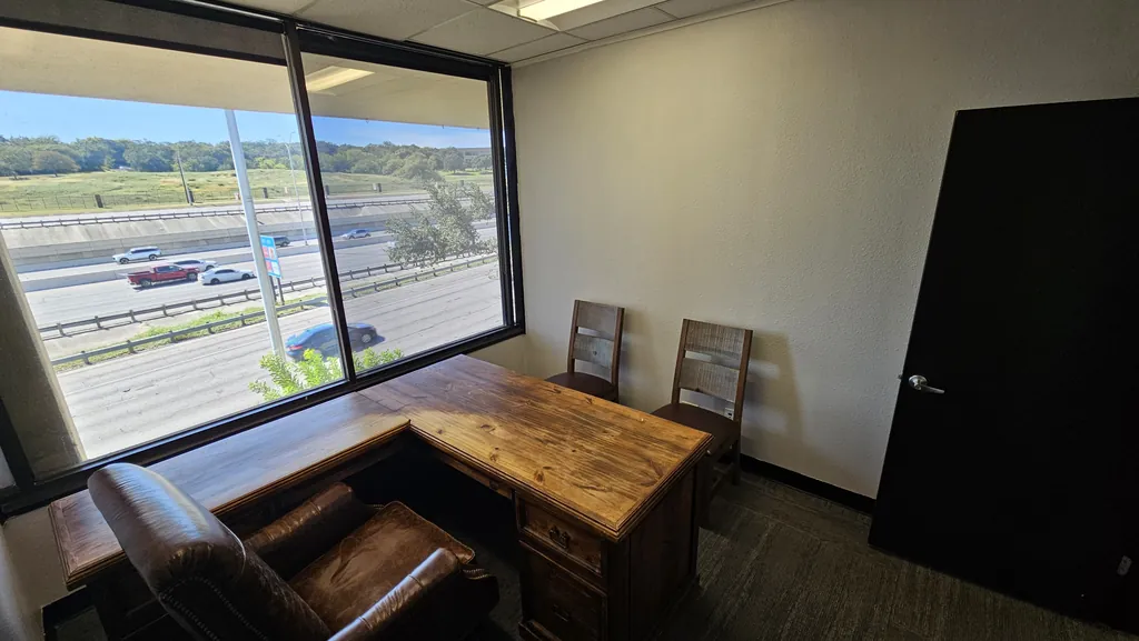 Private office in Suite 211 with an L-shaped wood desk and large windows over I-10