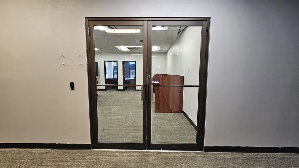 Double glass entry doors to private office Suite 211 with an access-control reader beside the door