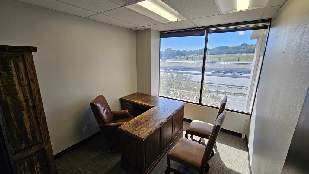 Private office in Suite 211 with an executive desk, two guest chairs, and a window view