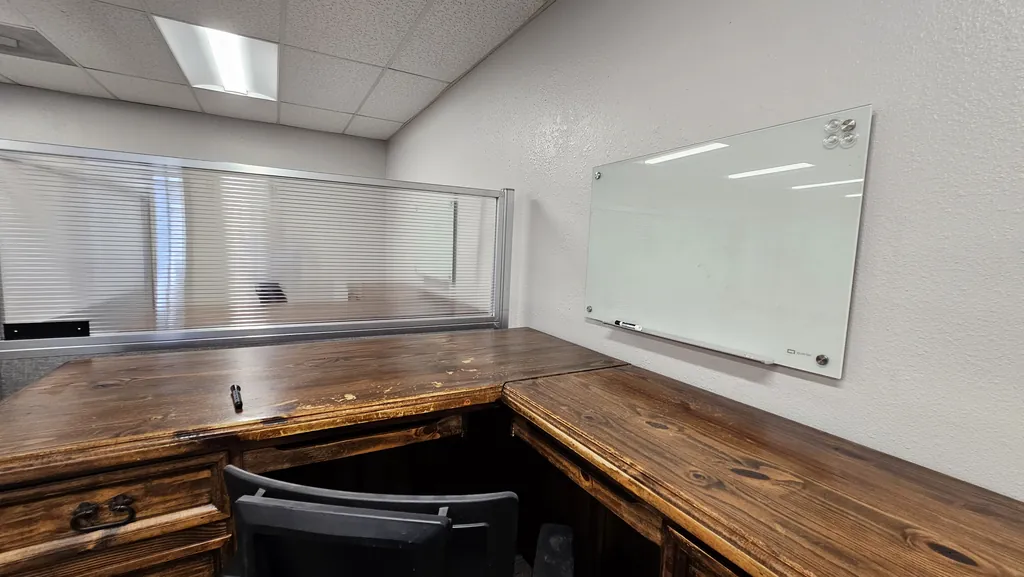 Corner workstation with a wall-mounted glass whiteboard in Suite 211