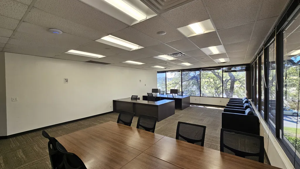 Room 221 conference table, executive desks, and lounge seating by the windows