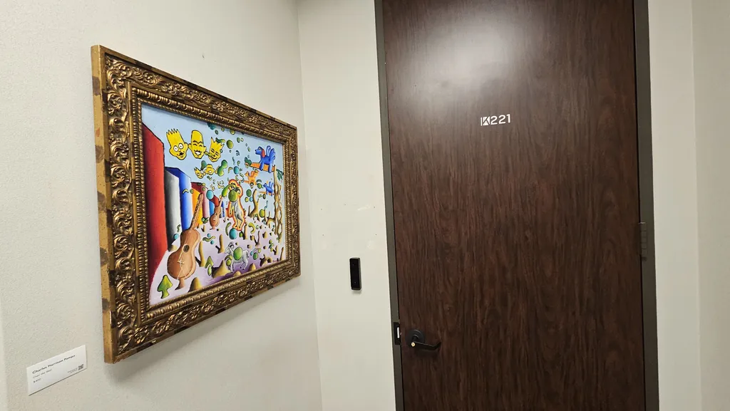 Suite 221 entry door with an access reader and framed artwork in the hallway